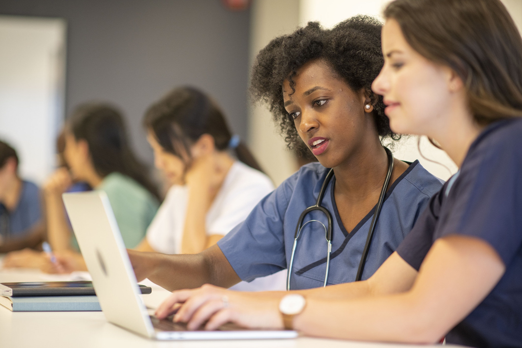 Two clinicians looking at a computer together in a classroom