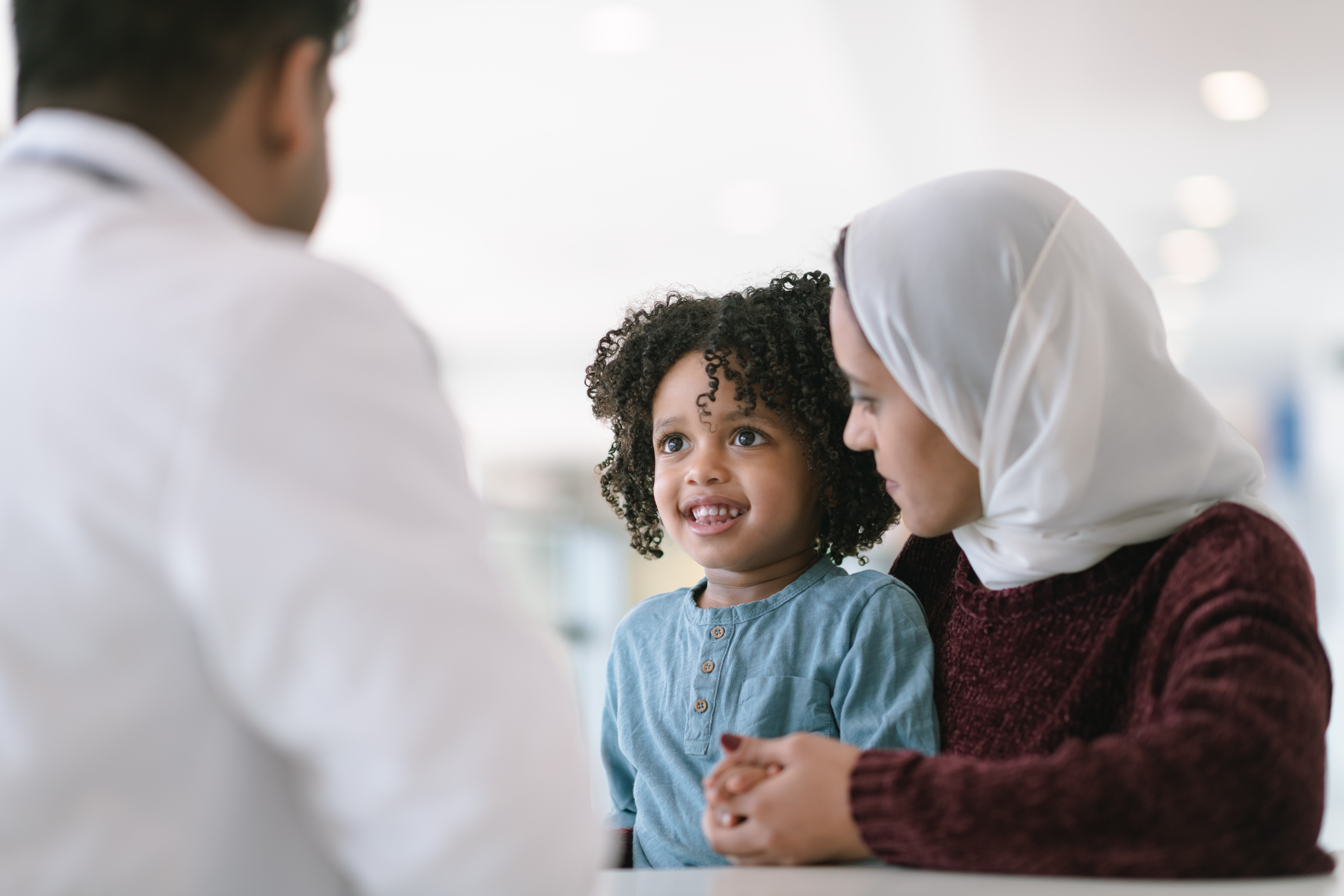 A woman with a small child talk with a physician