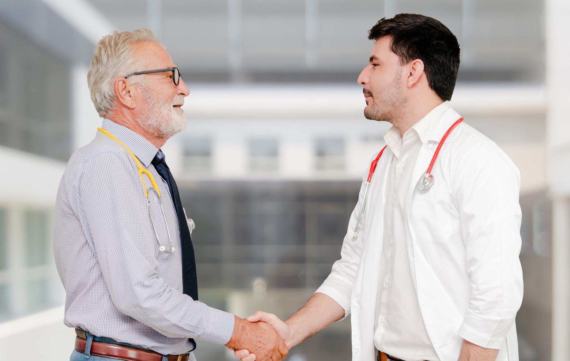 Older doctor shaking hands with younger doctor who is providing physician coverage for the facility.
