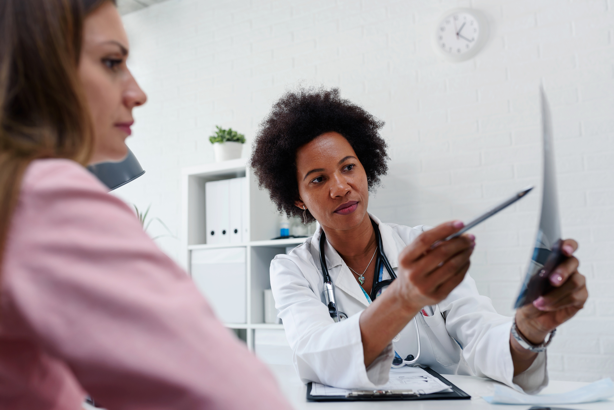 Woman reviewing xrays with female doctor providing physician coverage.
