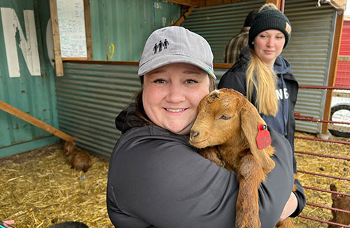CHG employee hugging a baby goat