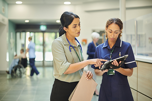 Hospital administrator talks to a provider about something they’re looking at on a tablet